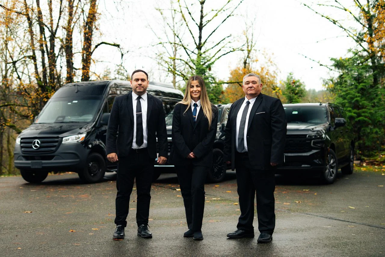 H Black Service Seattle chauffeur beside a black luxury vehicle